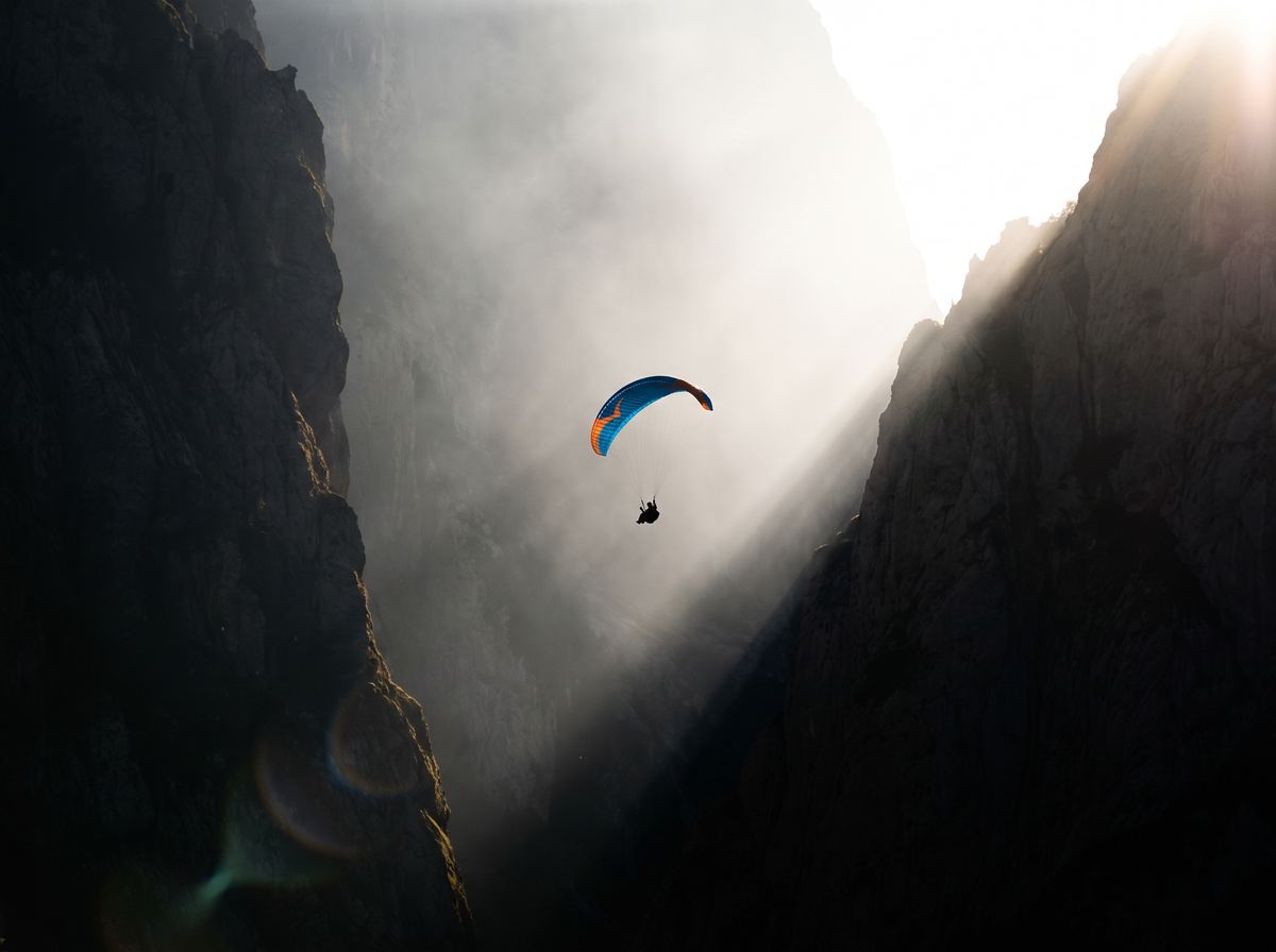 A paraglider between misty mountain cliffs with sun rays, generated with Seedream 5 Pro